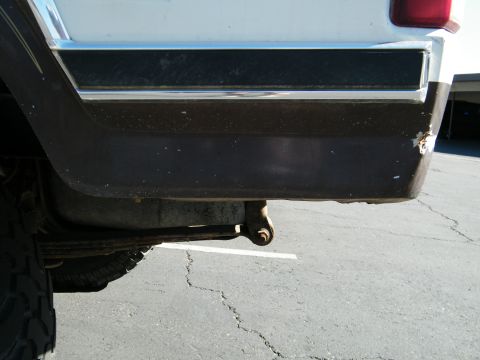 1982 Ford Bronco - Close-up view of the rear section of a white vehicle, highlighting the bumper, trim, and a portion of the tire.