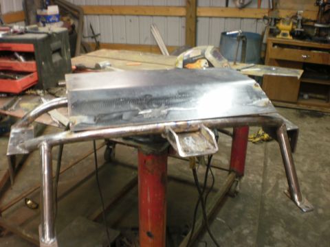 1995 Ford Bronco - A custom fabricated metal part, possibly for a roll cage, is shown on a stand in a workshop.