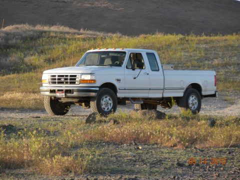 1989 Ford Bronco - This white Ford F-250 pickup truck, likely from the early 1990s, is parked on a dirt road.