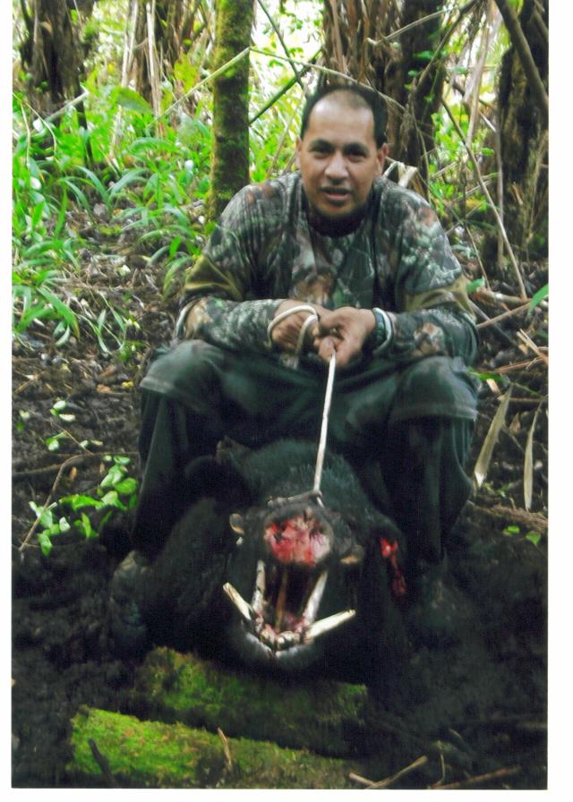 Hunter in camo crouching with a wild boar in a forest