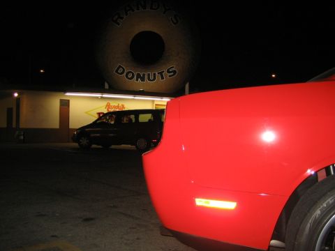 2010 Dodge Challenger - A red 2010 Dodge Challenger is parked at night in front of Randy's Donuts.