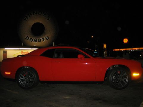 2010 Dodge Challenger - A red 2010 Dodge Challenger is parked at night in front of the iconic Randy's Donuts sign.