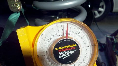 1995 Ford Bronco - Close-up of a yellow Johnson Magnetic Angle Locator No. 700 held against a driveline component under a vehicle, its red needle reading roug…