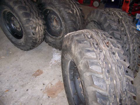 2001 Dodge 1500 - A collection of four large, tires and their rims are displayed on a concrete surface, likely for sale or storage.