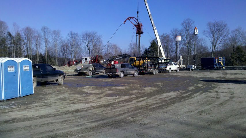 Construction scene with trucks, trailers, and portable toilets under a clear blue sky