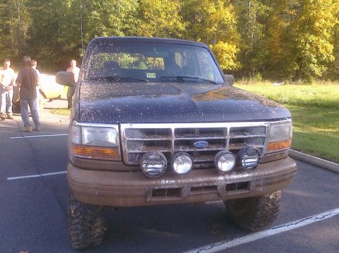 1995 Ford Bronco - This 1995 Ford Bronco is seen from the front, heavily covered in mud, with several auxiliary lights mounted on the bumper.
