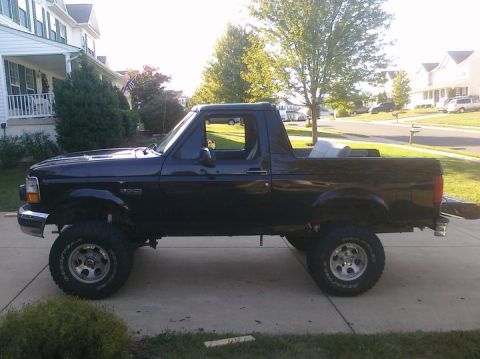 1995 Ford Bronco - Lifted 1995 Ford Bronco shown from the side on a paved driveway.