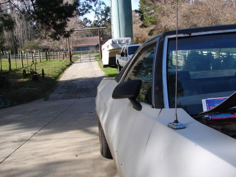 1973 Ford Ranchero - A light-colored sedan is parked on a driveway, with a farm gate and silo visible in the distance.
