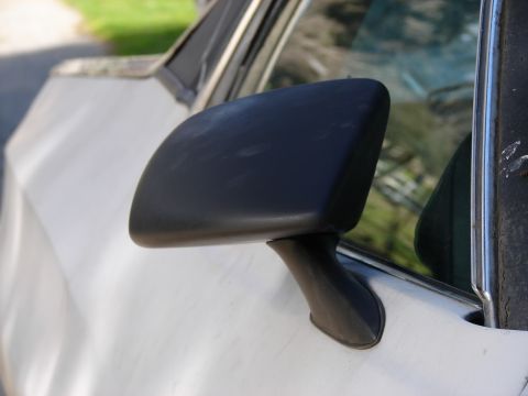 1973 Ford Ranchero - A close-up of a black side mirror mounted on the door of a white vehicle.