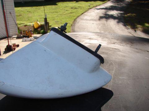 1973 Ford Ranchero - A white plastic part with visible bolts and rubber trim is shown against a blurred outdoor background.