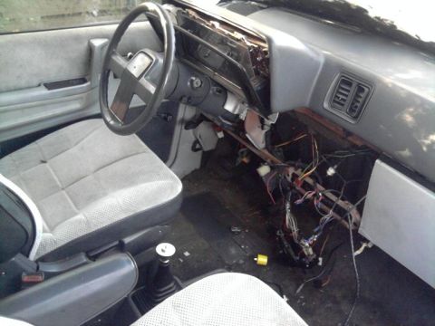 1989 Dodge Caravan - The interior of a vehicle shows exposed wiring and damaged dashboard components.