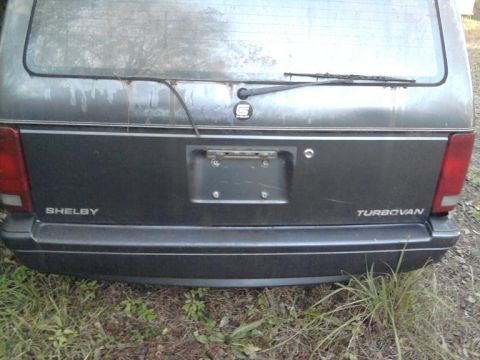 1989 Dodge Caravan - Rear view of a van with Shelby and Turbovan badging, showing its taillights and license plate area.