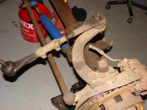 1971 International School Bus - Close-up view of various vehicle suspension components, including tie rods and a shock absorber, in a workshop setting.