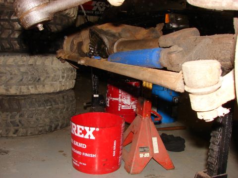 1971 International School Bus - Undercarriage view of a vehicle, showing mechanical components and tires, with various tools and containers nearby.