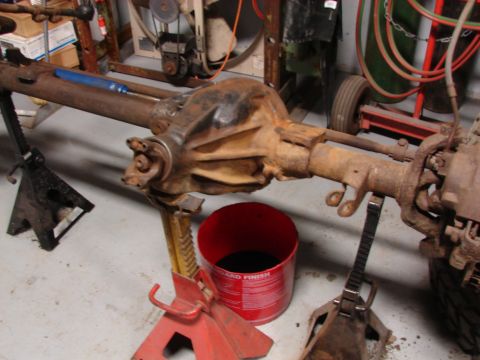 1971 International School Bus - A disassembled rear axle assembly is supported by jack stands in a workshop setting.