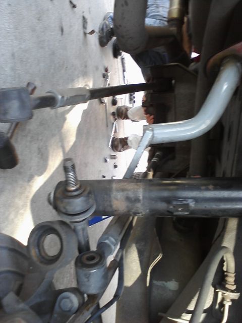 1995 Ford Taurus - Mechanic working on vehicle suspension components, with tools visible on the concrete floor.