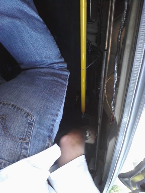 1995 Ford Taurus - A view from inside a vehicle, showing a person's legs and foot, with a yellow pole and exposed wiring visible.