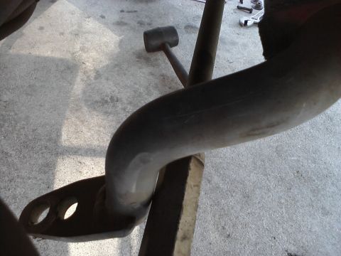 1995 Ford Taurus - A close-up view of a vehicle's exhaust pipe and suspension components on a concrete floor.
