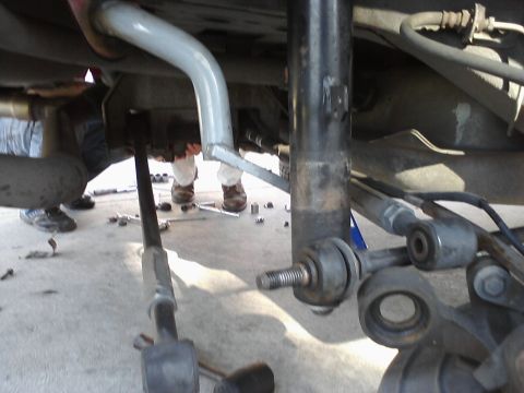 1995 Ford Taurus - Mechanics working on the rear suspension and exhaust system of a vehicle.