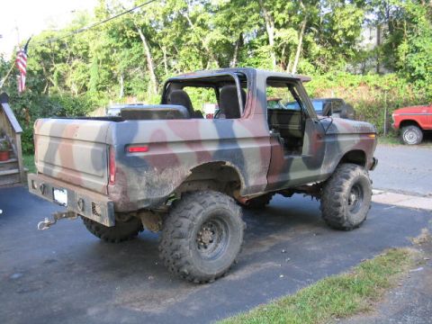1979 Ford Bronco - This camouflaged Ford Bronco is parked outside with its doors off and a tow hitch on the rear bumper.