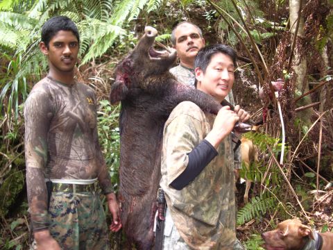 1991 Ford Bronco - Three hunters pose with a large wild boar they have successfully hunted in a wooded area.