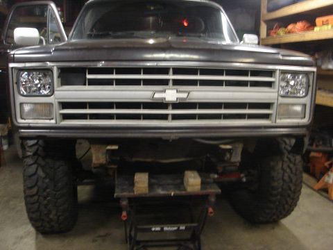 1989 Ford Bronco - This lifted Chevrolet K5 Blazer is on a jack stand, showing its front grille and large tires.