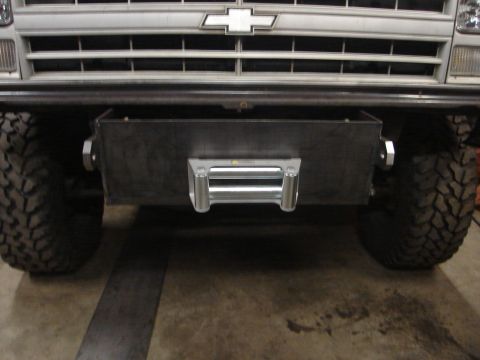1989 Ford Bronco - A vehicle's front end shows a custom bumper and winch, with large off-road tires.