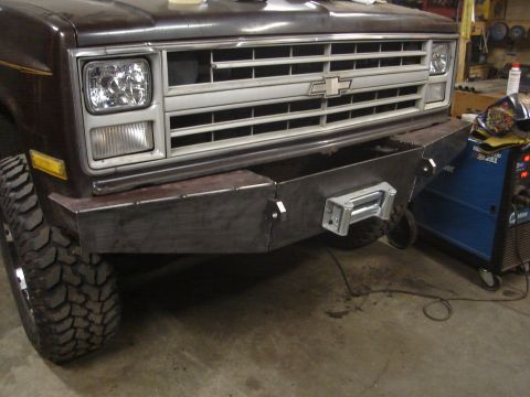 1989 Ford Bronco - Front view of a brown Chevrolet truck, a custom bumper and winch, with a visible Miller welding machine in the background.