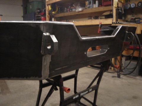 1989 Ford Bronco - A fabricated metal bumper sits on a portable workbench in a workshop setting.