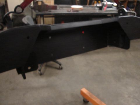1989 Ford Bronco - A black bumper is shown in a workshop, possibly undergoing repair or modification.