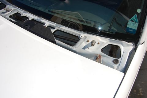 1994 Ford Bronco - The windshield cowl area of a white vehicle is shown, revealing exposed metal and a black trim piece.