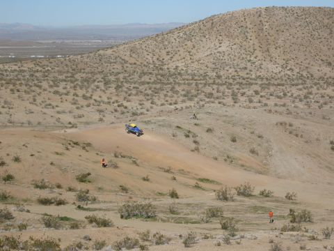 1986 Ford Bronco - Off-road vehicle navigates a desert terrain with sparse vegetation and hills in the background.