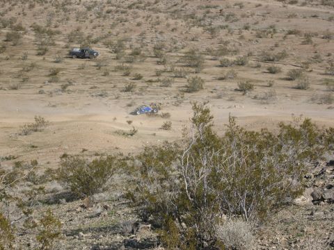 1986 Ford Bronco - Two off-road vehicles traverse a dusty desert terrain under a clear sky.
