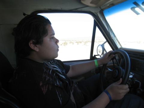 1986 Ford Bronco - A person is seen from the side driving a vehicle, with a watermark visible on the lower right.
