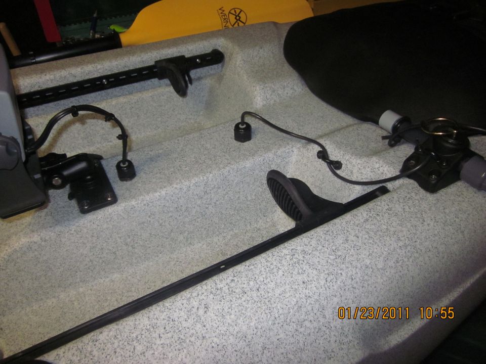 Kayak interior with foot braces, mounting hardware, and a yellow paddle visible