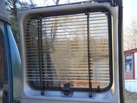 1981 Ford E350 - View through the rear window of a vehicle, showing horizontal blinds covering the glass.