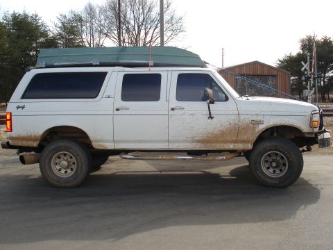 1992 Ford C-350 (Centurion Conversions) - This 1992 Ford C-350 Centurion Conversions truck is seen from the side, carrying a boat on its roof and covered in mud.