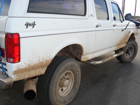 1992 Ford C-350 (Centurion Conversions) - This white 4x4 SUV is heavily coated in mud, showing its off-road capabilities with prominent running boards and a large exhaust pipe.