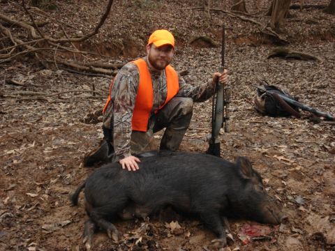 1992 Ford C-350 (Centurion Conversions) - A hunter poses with his wild boar kill in a wooded area, with hunting gear visible.