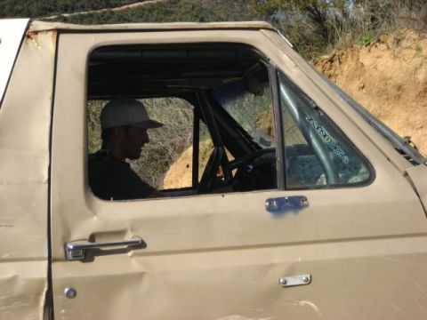 1989 Ford Bronco - Driver's perspective inside a tan 1989 Ford Bronco, showing the interior and roll cage.