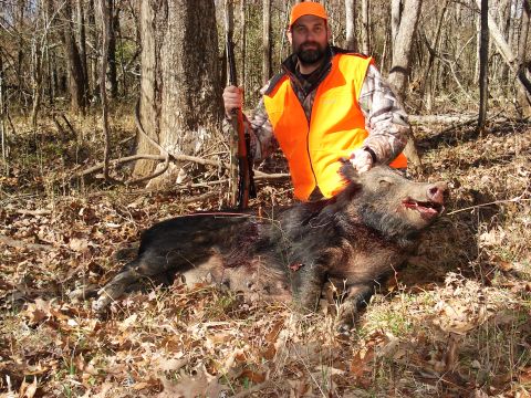 1992 Ford C-350 (Centurion Conversions) - A hunter poses with a wild boar he has successfully hunted in a wooded area.