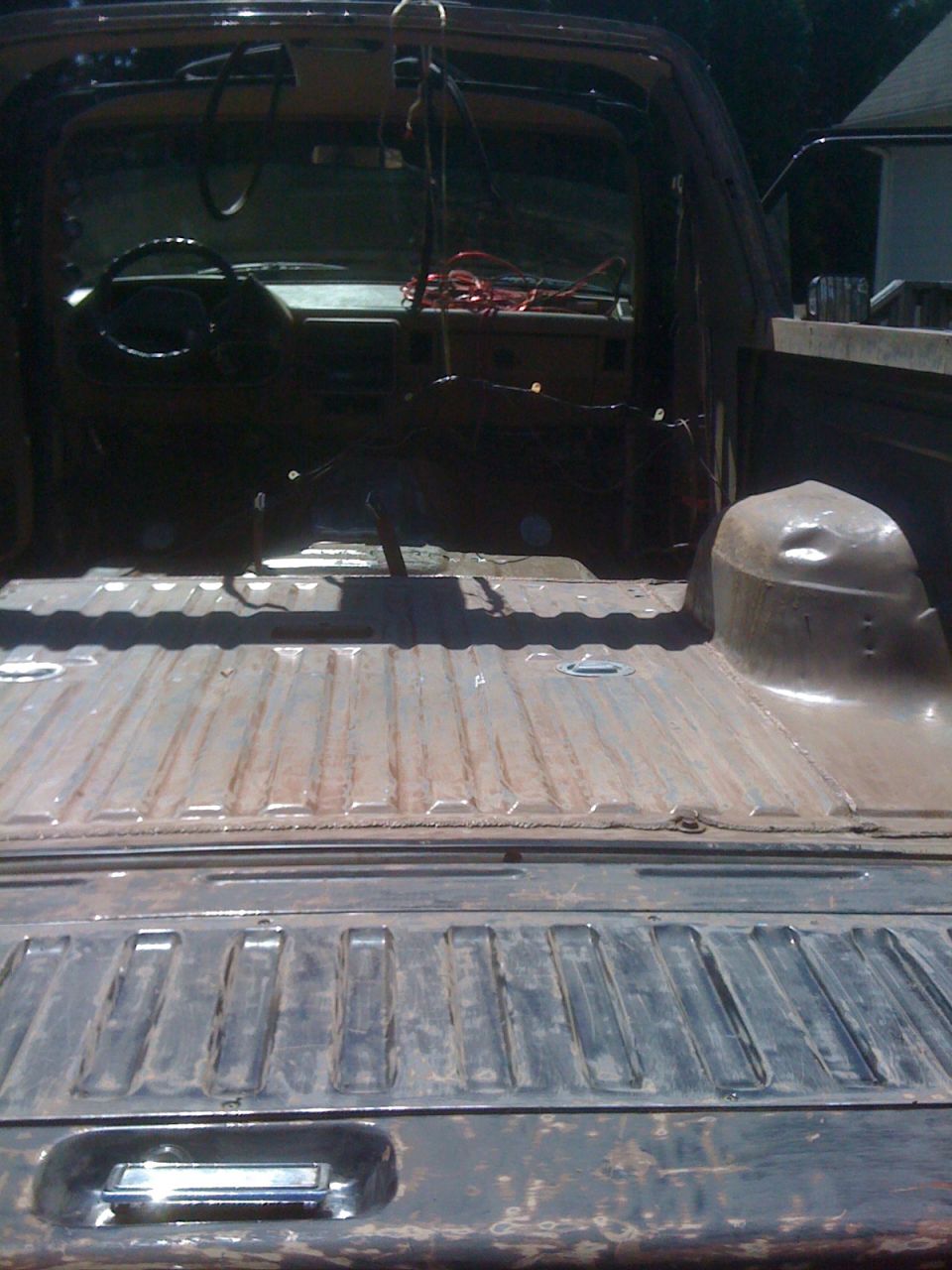 Stripped pickup truck bed and cab interior during restoration, viewed from the tailgate