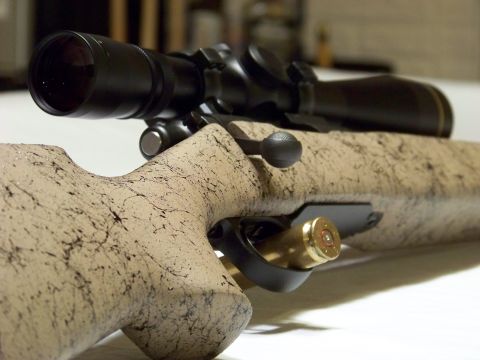 1995 Mercury Grand Marquis - A rifle with a scope and a cartridge loaded is shown in a close-up view.