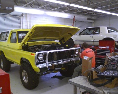 1978 Ford Bronco - A yellow 1978 Ford Bronco is being worked on in a garage, with another car visible in the background.