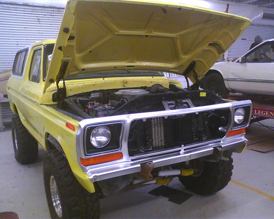Yellow 1978 Ford Bronco with hood open, showing engine bay. Front view