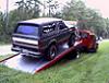 1991 Ford Bronco - A black 1991 Ford Bronco is loaded onto a red trailer, viewed from the rear three-quarter angle.