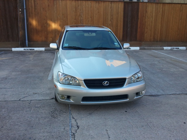 Silver Lexus IS300 parked in front of a wooden fence