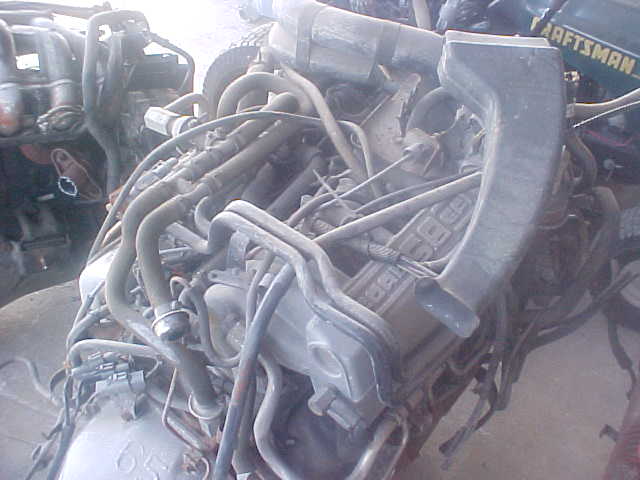 Engine with many hoses and tubes. Some text is visible on the engine block