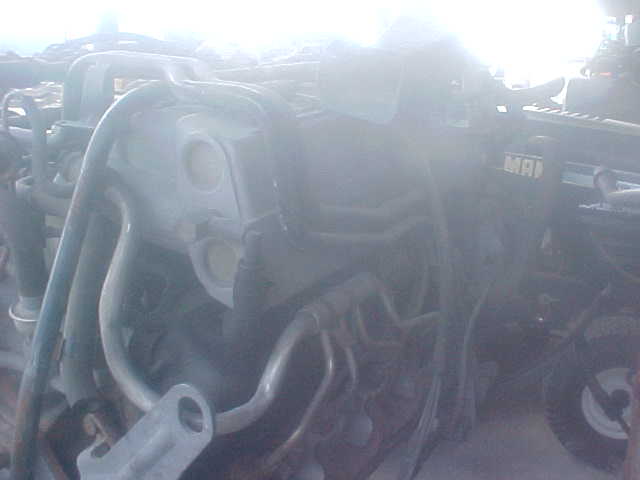 Engine parts with hoses and metal brackets. Text 'MAI' is visible on a dark component