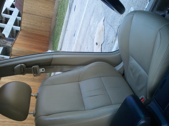 Tan leather car seats and door panel, with a seatbelt visible. A watermark reads SUPERMOTORS.NET